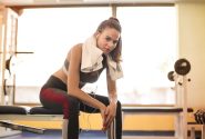 Woman in athletic wear taking a break at the gym with towel and earphones.